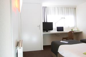 a room with a bed and a desk with a television at Campanile Nantes Saint-Sébastien-Sur-Loire in Saint-Sébastien-sur-Loire
