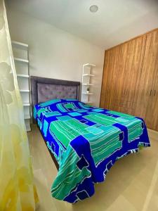 a bedroom with a blue and green comforter on a bed at Apartamento Familiar En Cartago in Marinita