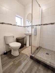 a bathroom with a toilet and a sink and a shower at Dune Whispers in Jeffreys Bay