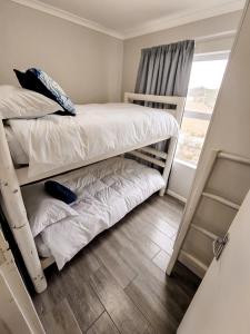 a bedroom with two bunk beds and a window at Dune Whispers in Jeffreys Bay +22 photos