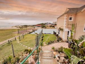 a house with stairs leading up to a body of water at Dune Whispers in Jeffreys Bay
