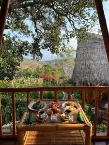 a table with plates of food on top of a balcony at Penida Bambu Green Villas in Nusa Penida