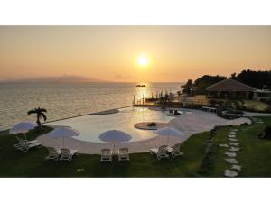 una piscina con sedie e ombrelloni di fronte all'oceano di Beach Hotel Sunshine Ishigakijima - Vacation STAY 95046v a Isola di Ishigaki