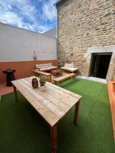 a patio with a wooden table and a brick wall at Maison de ville charmante in Quessoy