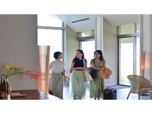 tre donne in piedi in una stanza con i bagagli di Beach Hotel Sunshine Ishigakijima - Vacation STAY 95045v a Isola di Ishigaki