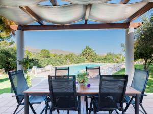 une table et des chaises en bois sur une terrasse dans l'établissement Villa New Charme, à Castellammare del Golfo