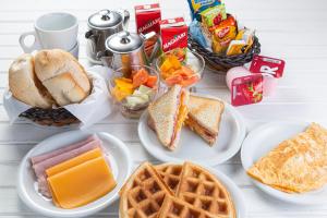 a white table topped with plates of food and waffles at Vitara Motel (Adult Only) in Taboão da Serra