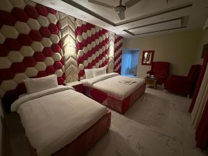 a hotel room with two beds and a chair at Dream Inn Guest House Islamabad in Islamabad