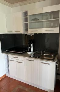 a kitchen with white cabinets and a sink at Allgäu Pension "Ab in den Süden" in Bernbeuren