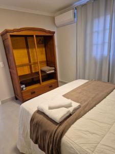 a bedroom with a bed and a dresser with towels on it at Acolhedor ao lado de Vinícola e Centro in Espirito Santo Do Pinhal