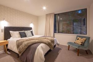 a bedroom with a bed and a chair and a window at Highlands Apt- Lake Views- Free Parking- AC- BBQ in Queenstown
