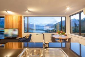 a living room with a table and a large window at Highlands Apt- Lake Views- Free Parking- AC- BBQ in Queenstown