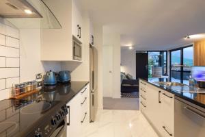 a kitchen with white cabinets and a sink at Highlands Apt- Lake Views- Free Parking- AC- BBQ in Queenstown +10 photos