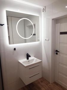 a white bathroom with a sink and a mirror at Leśna Przystań in Busko-Zdrój