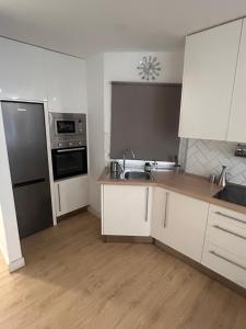 Una cocina con gabinetes blancos y electrodomésticos de acero inoxidable. en Padre Anchieta 35 - 5, en Santa Cruz de Tenerife