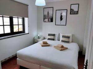 Un dormitorio con una cama blanca con dos toallas encima. en Baleal Classic Waves Guest House, en Baleal
