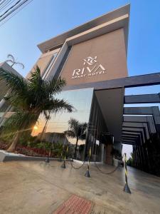 a building with a palm tree in front of it at Riva Apart Hotel in Campo Mourão +102 photos