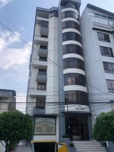 a tall white building with a sign in front of it at Amplio depto,parqueo,zona exclusiva in Cochabamba