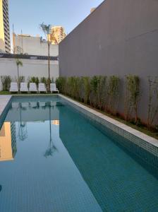 a swimming pool with chairs next to a building at Apto próximo terminal Barra Funda, Allianz e Fórum in Sao Paulo