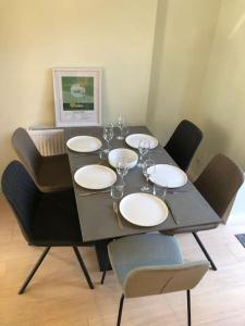 ein Tisch mit vier Stühlen und ein schwarzer Tisch mit Weingläsern in der Unterkunft Modern and comfortable stay in Morecambe in Morecambe