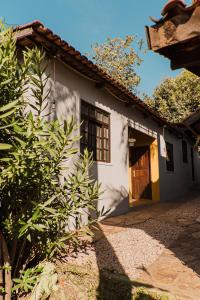 une maison blanche avec une porte et un arbre dans l'établissement FLATS COMFORT- Melhor CUSTOXBENEFÍCIO na charmosa Vila de São Jorge, Goiás, à Sao Jorge