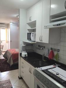 Una cocina con gabinetes blancos y encimera. en Nossa Kitnet no Sudoeste 10 minutos da Esplanada, en Brasilia