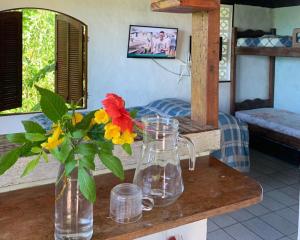 a vase with flowers on a table with a bedroom at Bangalô Pontal do Atalaia com piscina para casal ou família in Arraial do Cabo +17 photos