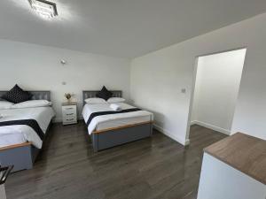 two beds in a room with white walls and wood floors at 5-Bedroom Cottage in New Waltham, Grimsby in Grimsby