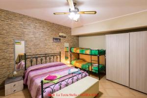 a bedroom with two bunk beds and a brick wall at Casa Albergo La Terza Stella in Agira