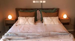 a bed with pillows and two lights on two tables at Blizu in Villa La Angostura