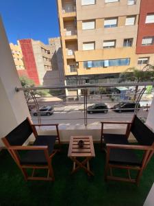 a balcony with two chairs and a table and a building at Appartement Moderne à El Qods in Oujda