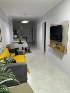 ein Wohnzimmer mit einem Sofa und einem Fernseher an der Wand in der Unterkunft CasaAju - Sua nova opção de hospedagem em Aracaju, reformada e toda mobiliada, com tudo novinho, no capricho só para você in Aracaju
