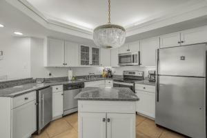 a kitchen with white cabinets and a stainless steel refrigerator at Summer House 103A by Vacation Homes Collection in Orange Beach