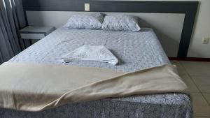 a bed with a blanket and a robe on it at Executive Celita Franco in Feira de Santana