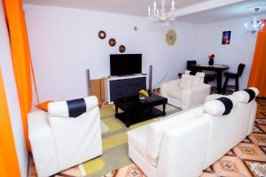 een woonkamer met twee witte banken en een televisie bij Crystal Home in Douala