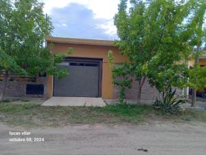 a house with a garage and a tree in front of it at Depto Ideal in Deán Funes