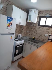 a kitchen with white appliances and a wooden counter top at Depto 41 in Santa Teresita