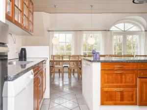 a kitchen with wooden cabinets and a dining room at 4 star holiday home in Ulfborg in Ulfborg