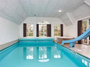 a swimming pool with a slide in a building at Luxury Retreat with Pool in Ulfborg