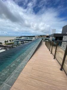 een houten promenade die naar het strand en de oceaan leidt bij sol flat cabo branco 50 metros do mar in João Pessoa