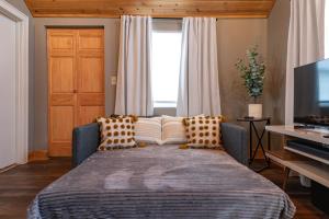 1 dormitorio con 1 cama con almohadas y TV en Charming Benson Home - Sleeps 5 Hot Tub!, en Omaha