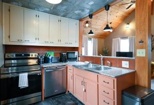 una cocina con fregadero y estufa en Charming Benson Home - Sleeps 5 Hot Tub!, en Omaha