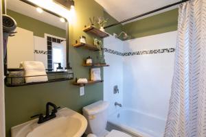 Un baño con lavabo, inodoro y espejo. en Charming Benson Home - Sleeps 5 Hot Tub!, en Omaha 11 fotos más