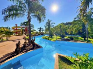 a pool at a resort with palm trees at Hotel Savana in Olímpia