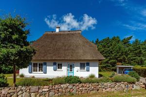 a thatch roof house with a stone wall at Haus 172, Lärchenweg 1 in Ostseebad Karlshagen