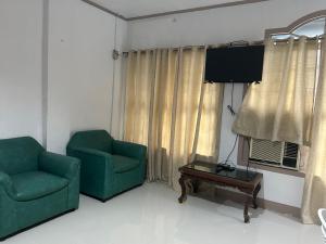 ein Wohnzimmer mit zwei Stühlen und einem Tisch und einem Fernseher in der Unterkunft En Pensionne Pension House in Iloilo City