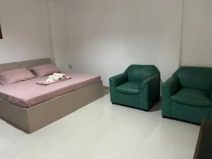 Zimmer mit einem Bett und zwei grünen Stühlen in der Unterkunft En Pensionne Pension House in Iloilo City