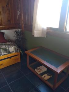 a room with a table next to a bed at Cabañas SurEnya in El Bolsón
