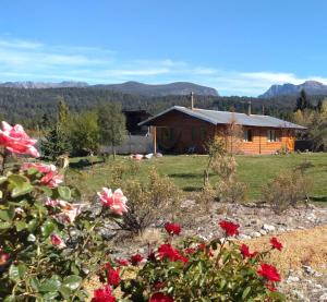 a log cabin with flowers in front of it at Cabañas SurEnya in El Bolsón