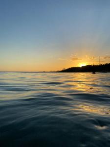 ein großes Gewässer mit dem Sonnenuntergang im Hintergrund in der Unterkunft Flat Pé na Areia Iriri T03 - Conforto a 3 Min da Praia in Anchieta + 6 Fotos